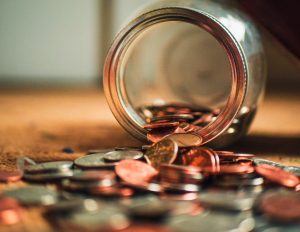 coins spilling out of a piggy bank glass jar